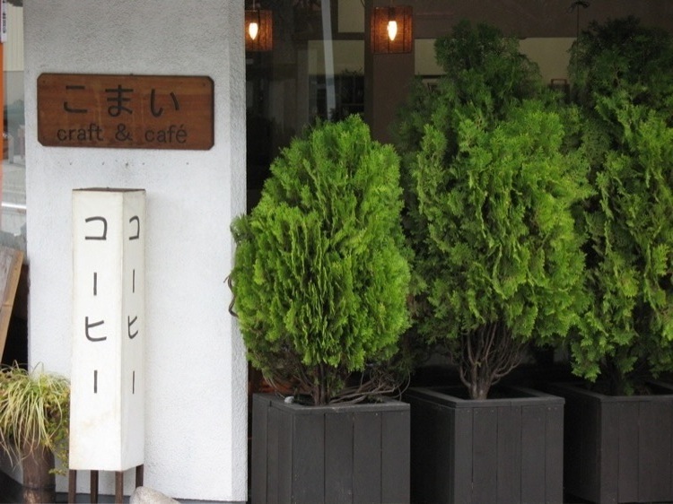 A picture of bushes and a sign for a coffee shop in Japan.