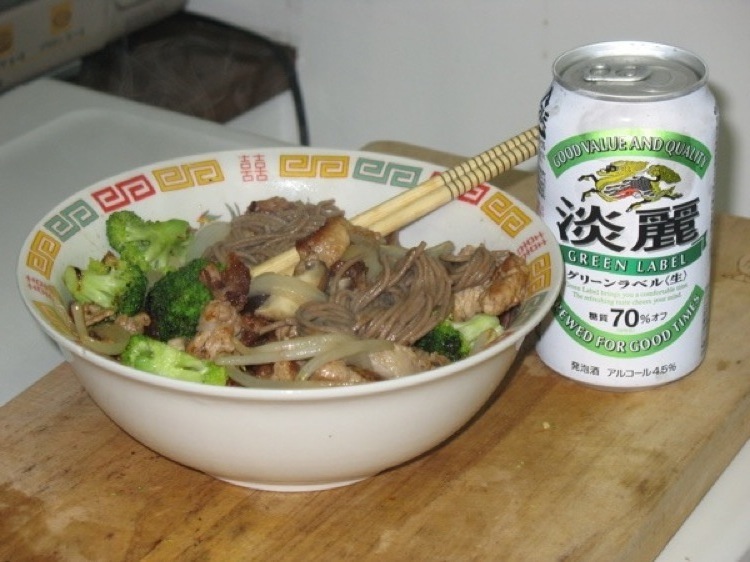 A bowl filled with stirfry, and a can of beer.