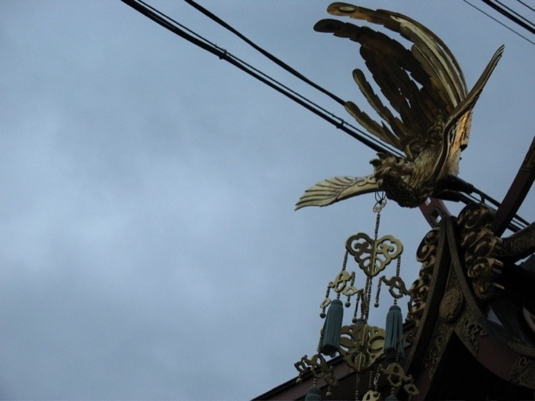 A golden bird on a float in a parade.