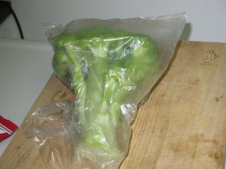 A head of broccoli in a plastic bag.