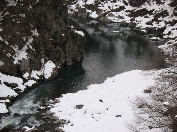 Snow surrounding tranquil water.